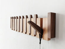 Piano key coat rack detail — fold-out wooden pegs and clean timber frame