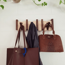 Piano key coat rack with pegs folded down — space-saving wooden wall rack in natural finish