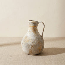 Rustic wabi-sabi pitcher vase on linen against cream plaster wall